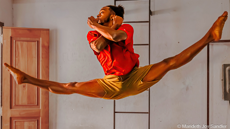 Male dancer in orange leaping into the air