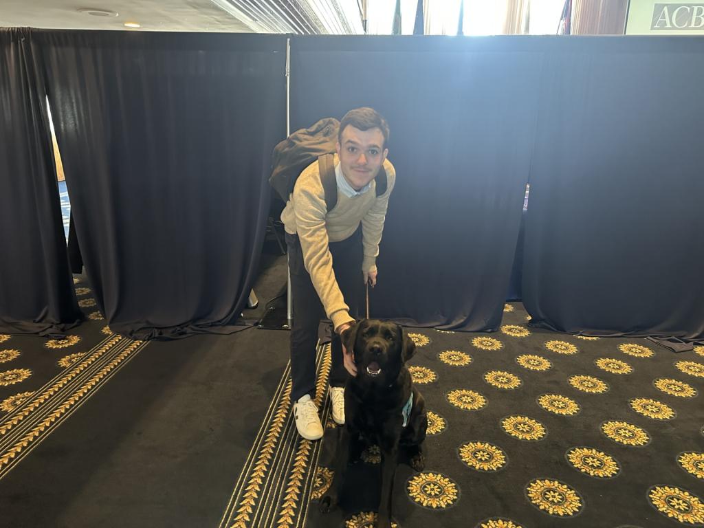 Photo of service dog Armand and furloughed VOA reporter.